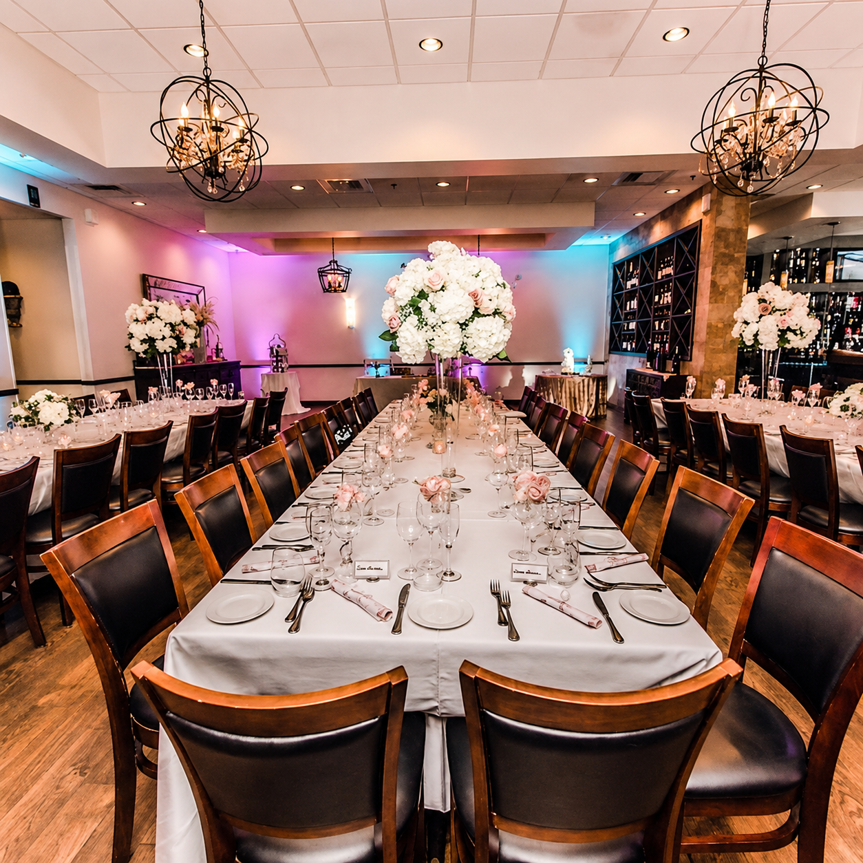 Rehearsal dinner setup with chandeliers and pink napkins